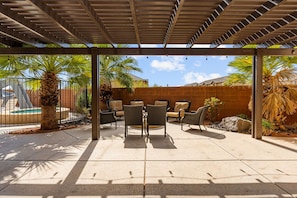 An outdoor patio with a pergola, seating area, and pool. - Grand Resort #98 9 Bedroom Home (Ivins)
