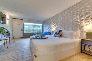 A modern hotel room with a bed, a desk, and a chair. There is a window with a view of the outside. - < 2 Mi to Disney! Walkable Condo w/ Pool Access (Kissimmee)