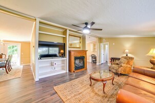 A living room with a fireplace, a television, and a ceiling fan.