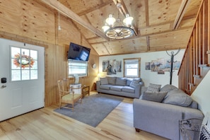 A wooden interior with a sofa, a television, and a fireplace.