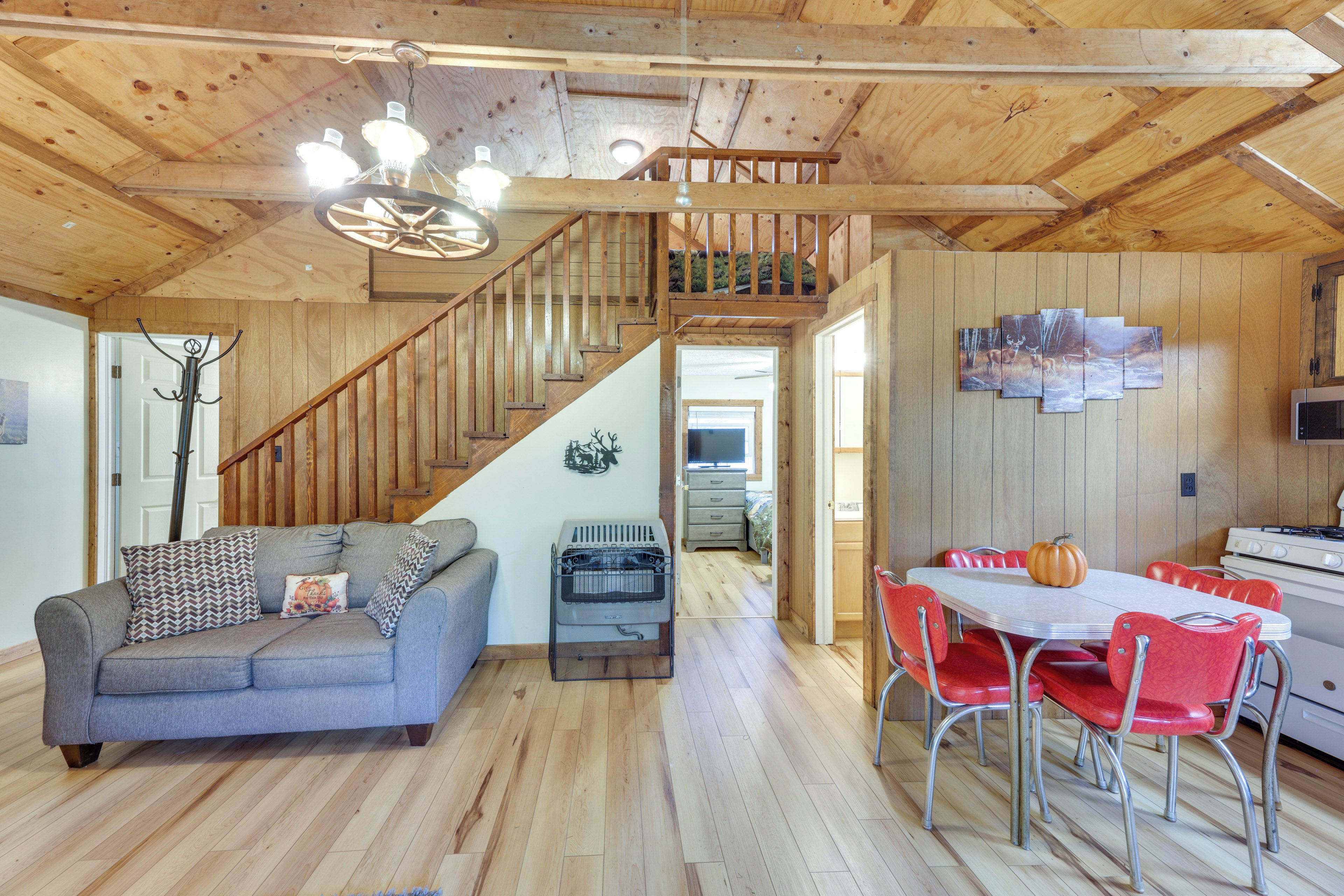 A wooden interior with a sofa, dining table, chairs, a staircase, and a kitchen area.