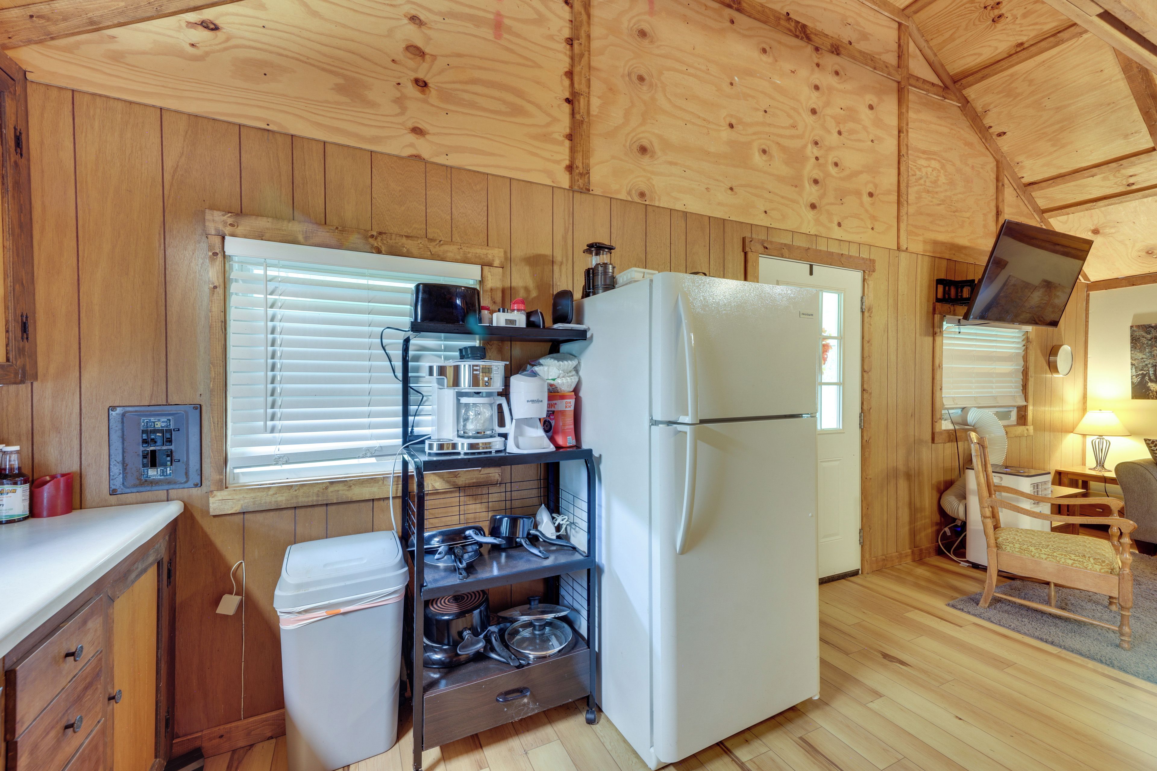 A compact kitchen with wooden walls, a white refrigerator, a coffee maker, and a stove.
