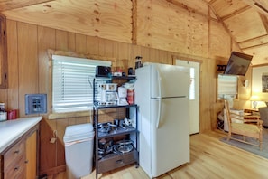 A compact kitchen with wooden walls, a white refrigerator, a coffee maker, and a stove. - Fish the Right Fork River: Tallmansville Home (Tallmansville)