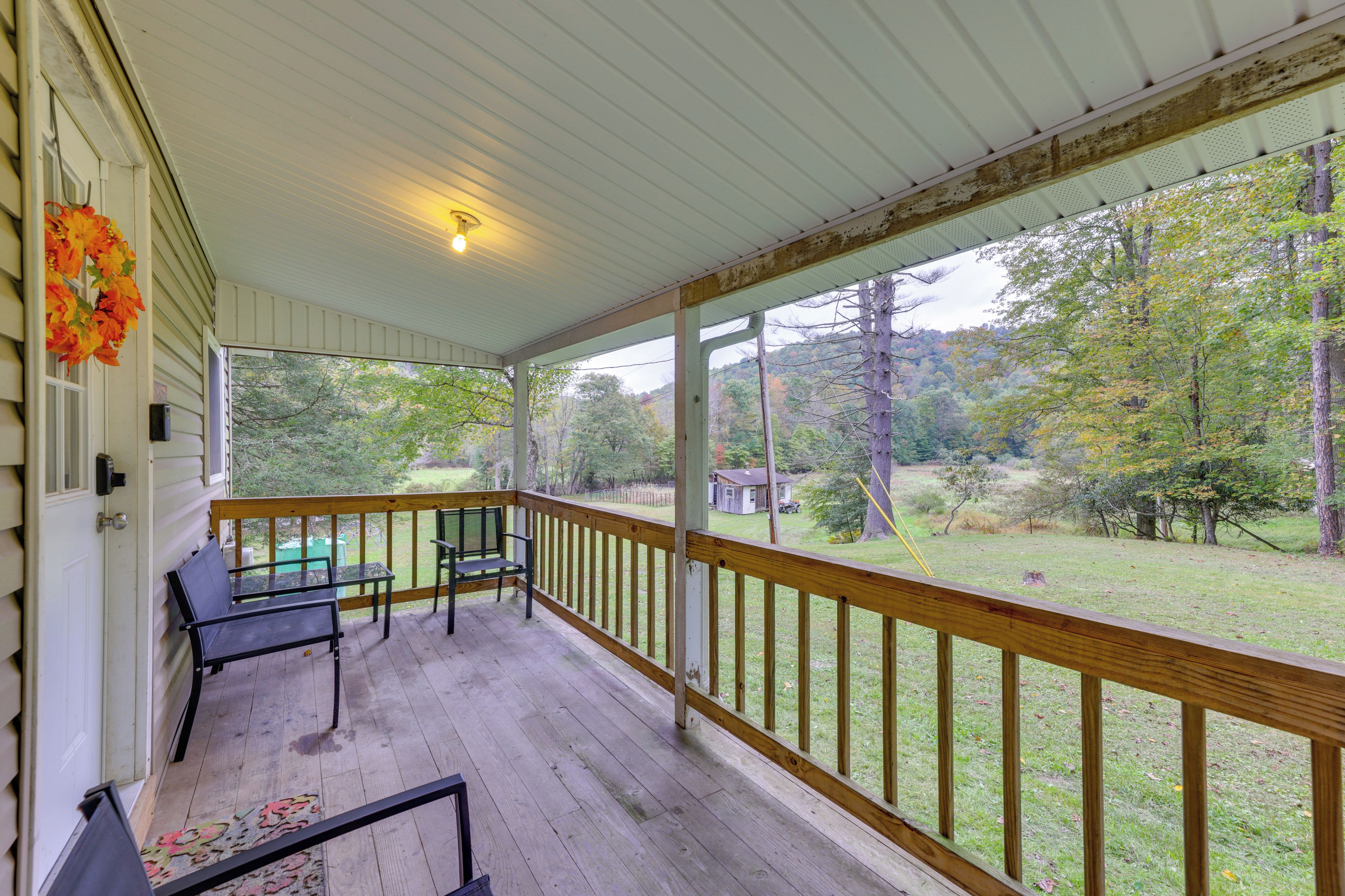 A covered porch with a wooden railing, a bench, and a table.