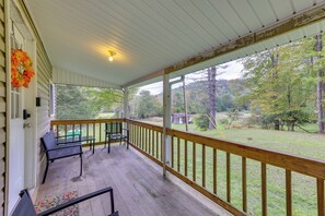 A covered porch with a wooden railing, a bench, and a table. - Fish the Right Fork River: Tallmansville Home (Tallmansville)