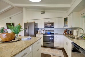 A modern kitchen with white cabinetry, stainless steel appliances, and a granite countertop. - Oceanfront Gem! Steps to Sand, Miles From Ordinary (Vero Beach)