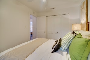 A bedroom with a bed, pillows, a bedside lamp, and a wardrobe. - Oceanfront Gem! Steps to Sand, Miles From Ordinary (Vero Beach)