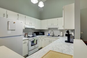 A modern kitchen with white cabinets, a built-in oven, a microwave, and a coffee machine.