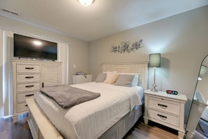 Een slaapkamer met een bed, nachtkastjes, een televisie, een lamp en een decoratie aan de muur.