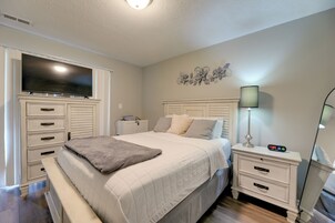 A bedroom with a bed, bedside tables, a TV, a lamp, and a wall decoration.