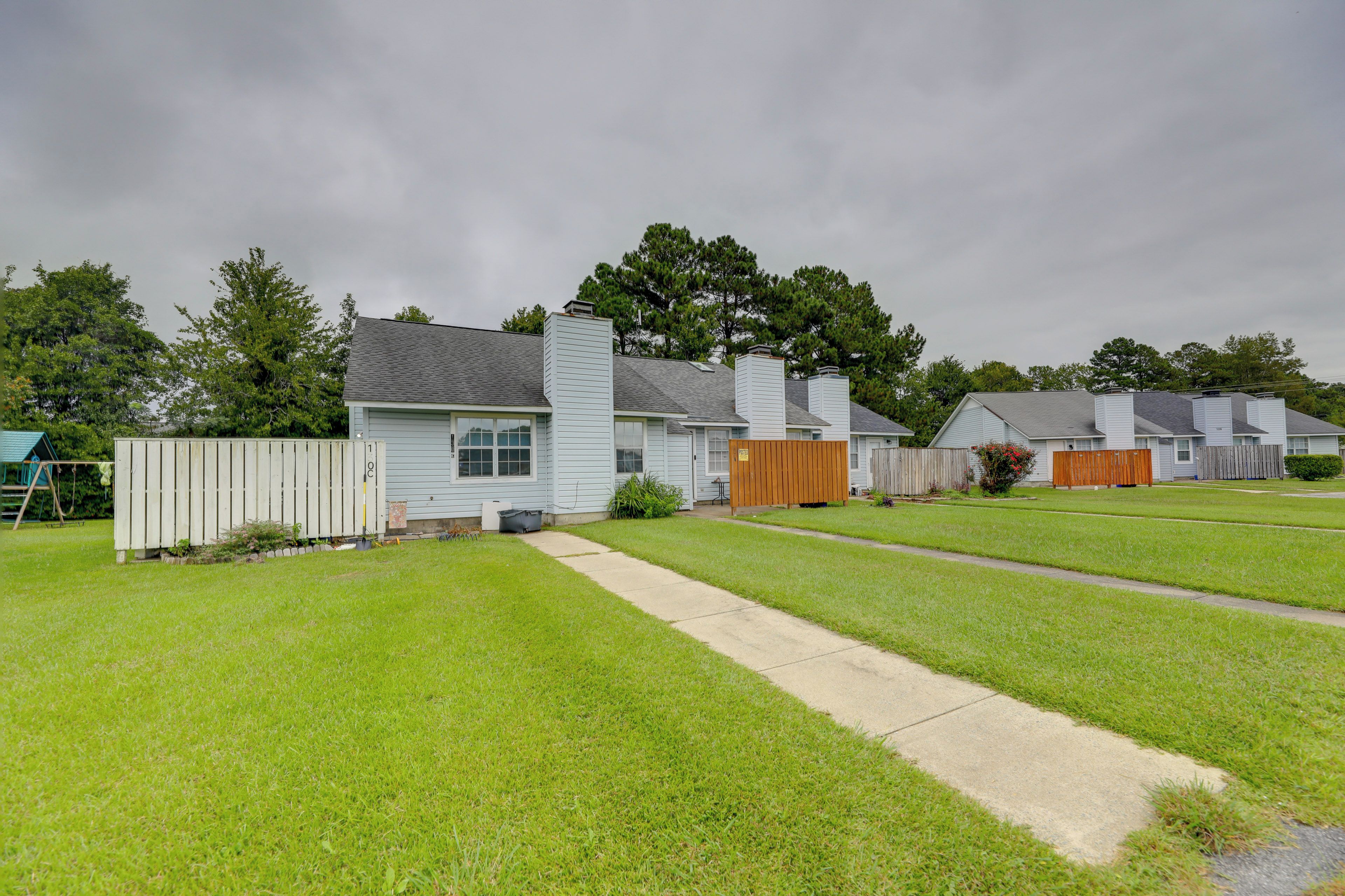 A residential area with houses, a grassy yard, and a wooden fence.