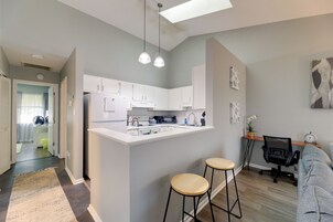 Una cocina moderna con armarios blancos, una isla central y taburetes de bar.