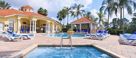 A swimming pool area with lounge chairs and a covered seating area.