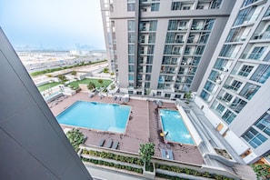 A high-rise building with a rooftop swimming pool and lounge area. - Stayshort - Cosy 1 Bedroom in MBR City Sleeps 4 With Balcony (Dubai)