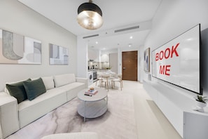A modern living room with a sofa, coffee table, and artwork on the walls. - Stayshort - Cosy 1 Bedroom in MBR City Sleeps 4 With Balcony (Dubai)
