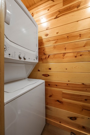 Eine weiße Waschmaschine und ein Trockner in einem Raum mit Holzvertäfelung.