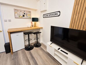 A compact living space with a kitchenette, a flat-screen TV, and a bar area. - 1-bed Apartment in Manchester City Center (Manchester)