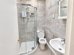 A modern bathroom with a glass-enclosed shower, a toilet, and a sink. - 1-bed Apartment in Manchester City Center (Manchester)