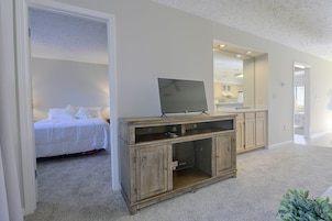 Un dormitorio con una cama, un armario de madera y un televisor.