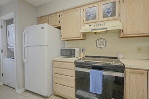 A compact kitchen with a refrigerator, microwave, stove, and wooden cabinets.