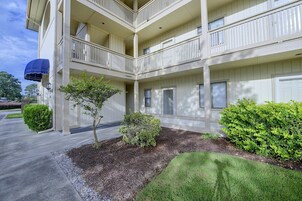A multi-story building with a covered outdoor area, a small tree, and well-maintained landscaping.