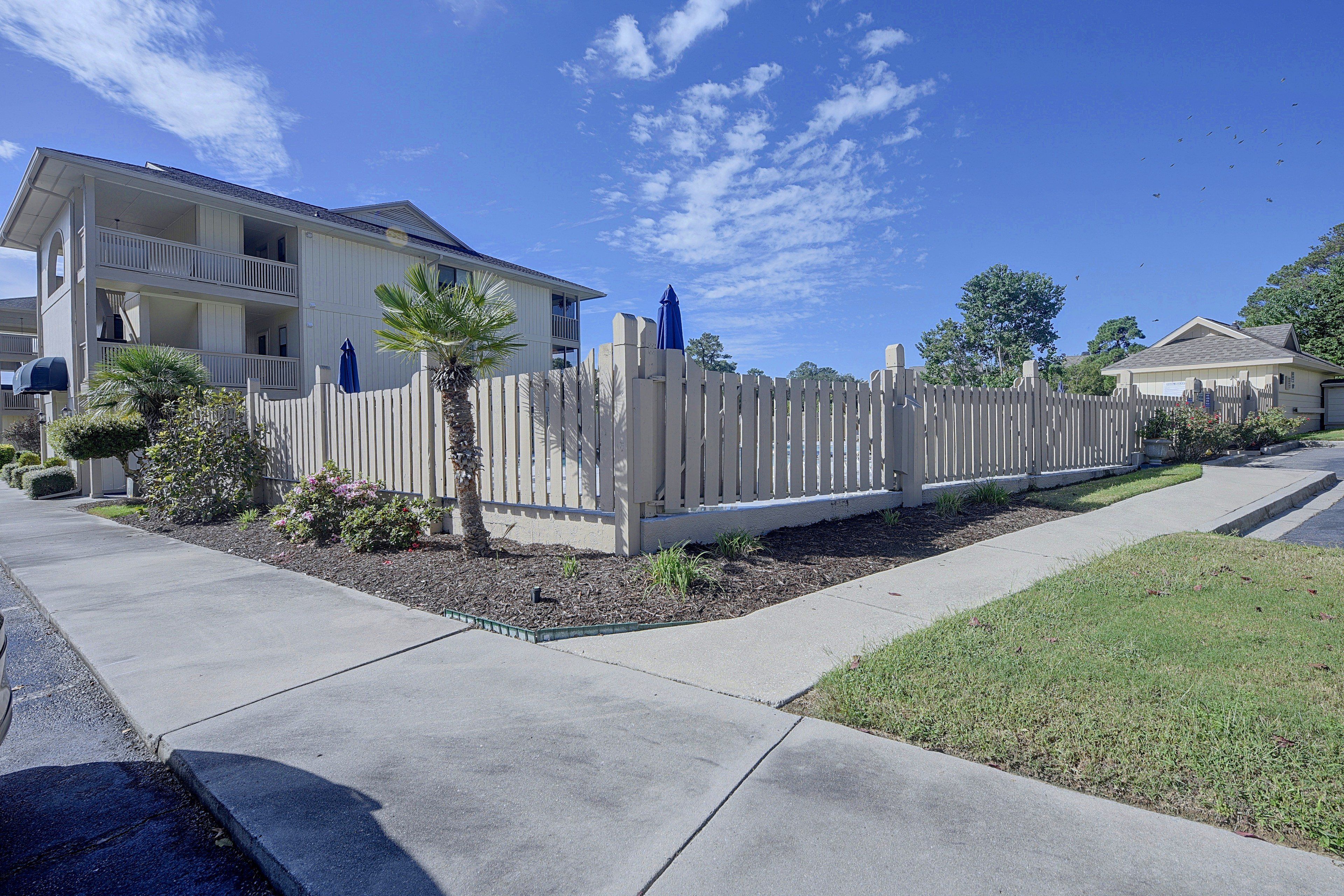 A residential area with a two-story house, a wooden fence, and a well-maintained lawn.