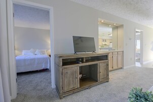 Un dormitorio con una cama, un armario de madera y un televisor.