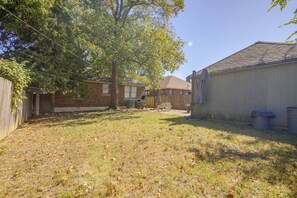 A backyard with a tree, a brick house, and a wooden fence. - Midtown Memphis Home w/ Home Gym & Office (Memphis)
