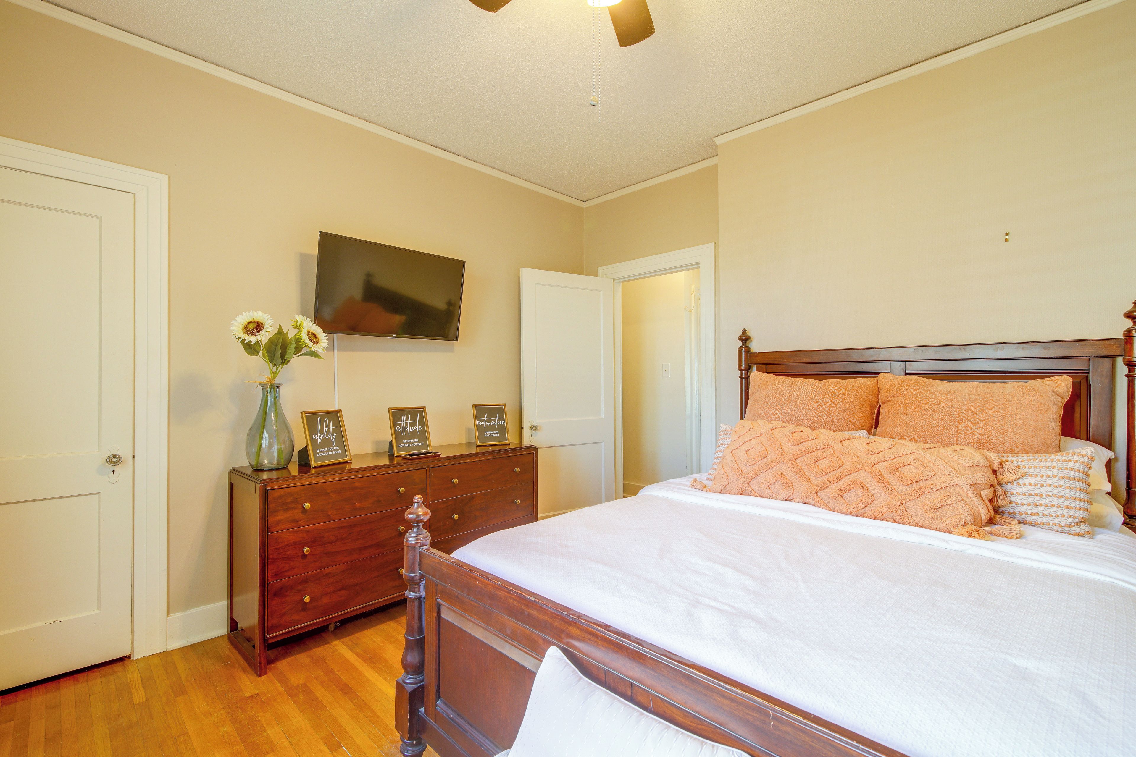 A bedroom with a bed, dresser, and a television on the wall.