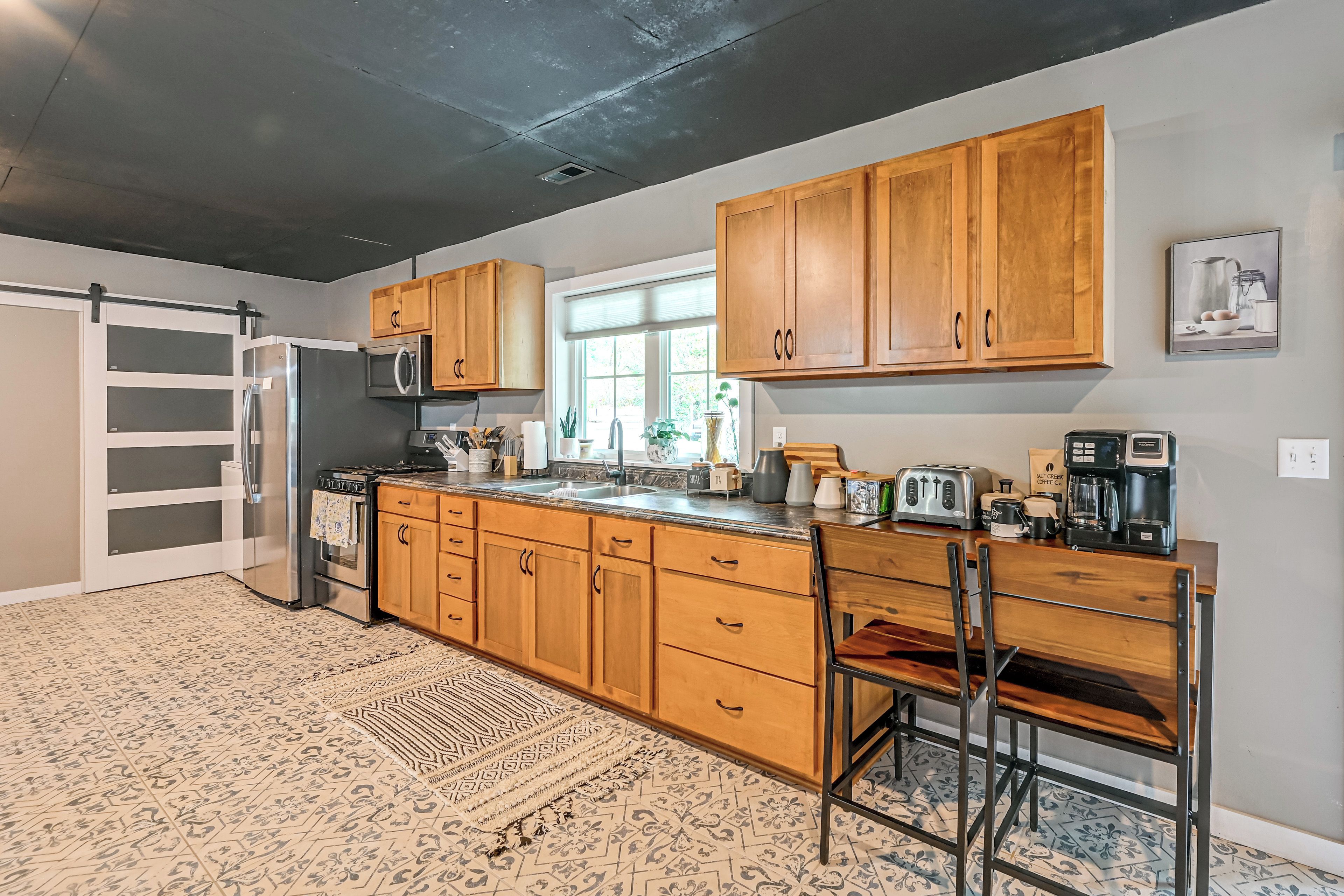 A kitchen with wooden cabinets, a stainless steel refrigerator, a microwave, a stove, and a coffee maker.