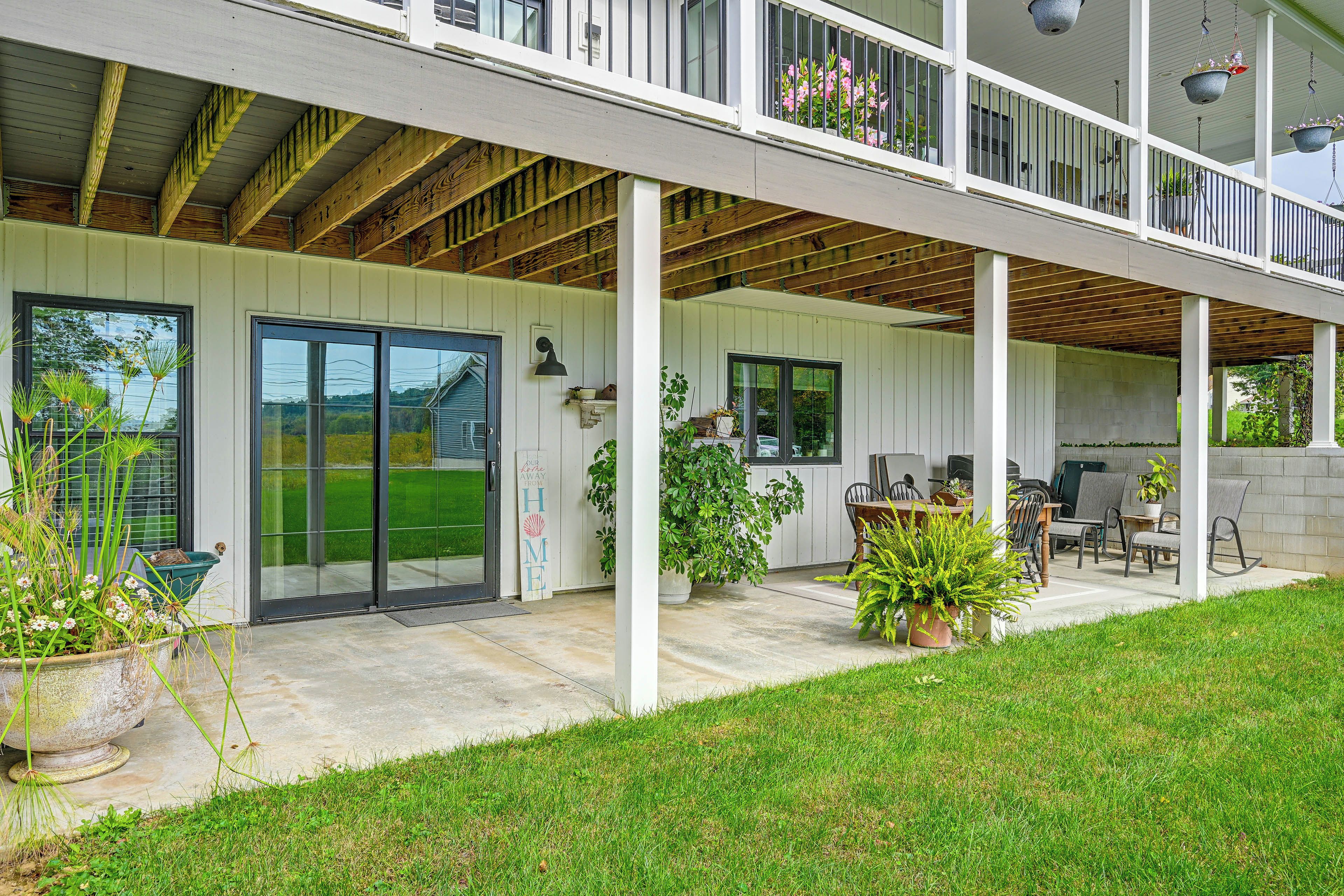 A covered patio area with a dining table and chairs, a small seating area, and a view of a green lawn.