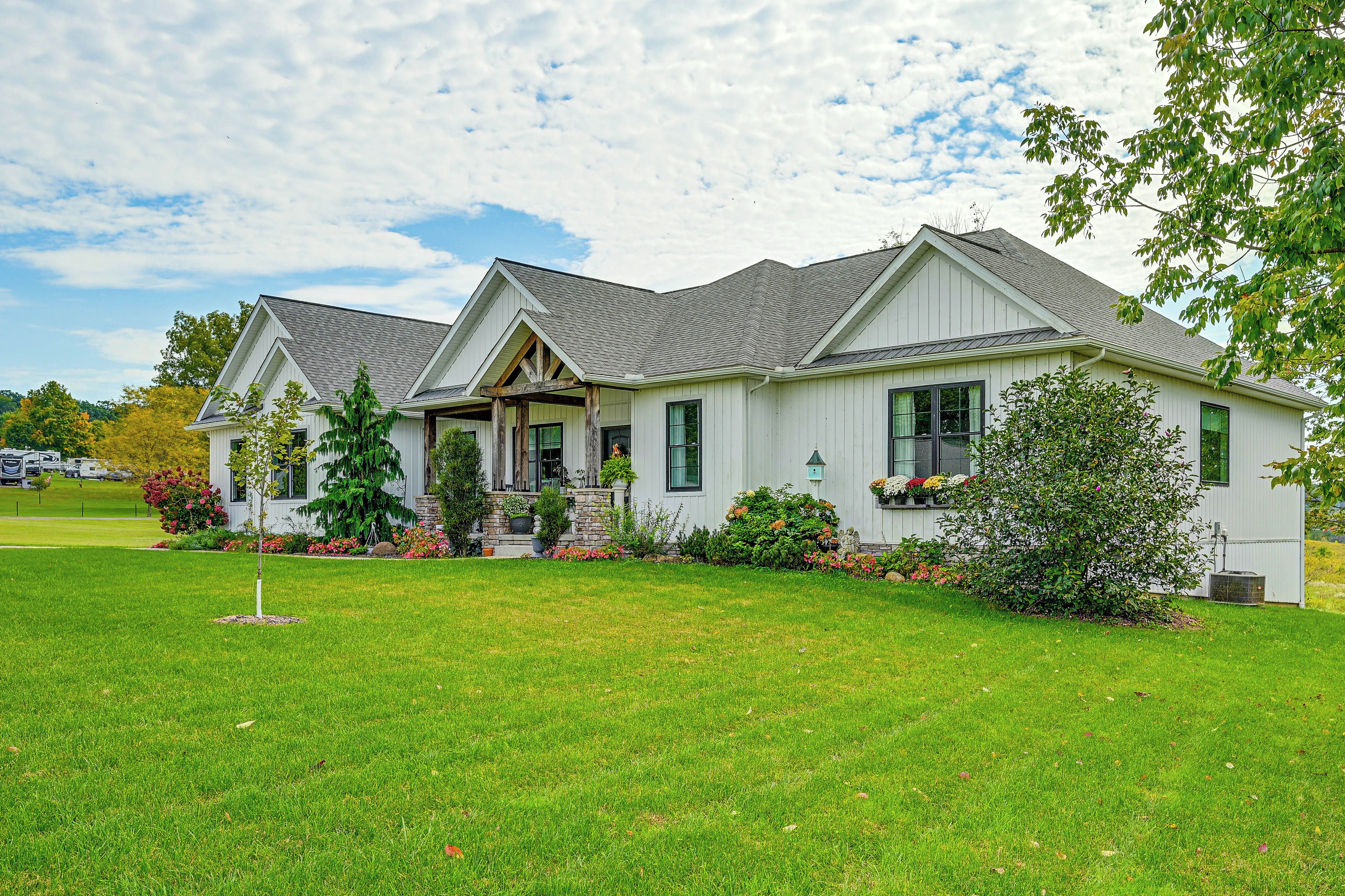 A two-story house with a front porch, a stone foundation, and a well-maintained lawn.
