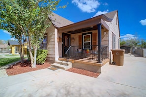 A two-story house with a front porch, a staircase leading to the entrance, and a small garden area with mulch and a tree. - Big Spring 'bison House' w/ Patio & Yard! (Big Spring)