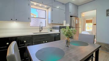 Una cocina moderna con armarios grises, un refrigerador de acero inoxidable y una mesa de comedor con dos sillas.