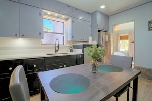 A modern kitchen with grey cabinets, a stainless steel refrigerator, and a dining table with two chairs. - Big Spring 'bison House' w/ Patio & Yard! (Big Spring)