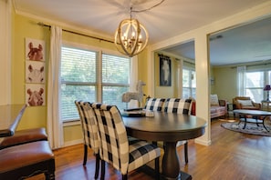 A dining area with a round table, checkered chairs, and a chandelier. - Adorable 1930s Cottage: Downtown + Dog Friendly (Granbury)
