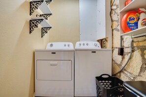A laundry area with two white Maytag washers and dryers, a black laundry basket, and a shelf with Tide detergent. - Adorable 1930s Cottage: Downtown + Dog Friendly (Granbury)