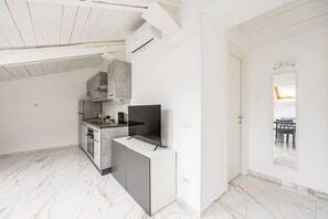 A modern kitchen with marble flooring, a built-in stove, and a small dining area with a table and chairs. - Cozy Slooping Rooftop (Naples)