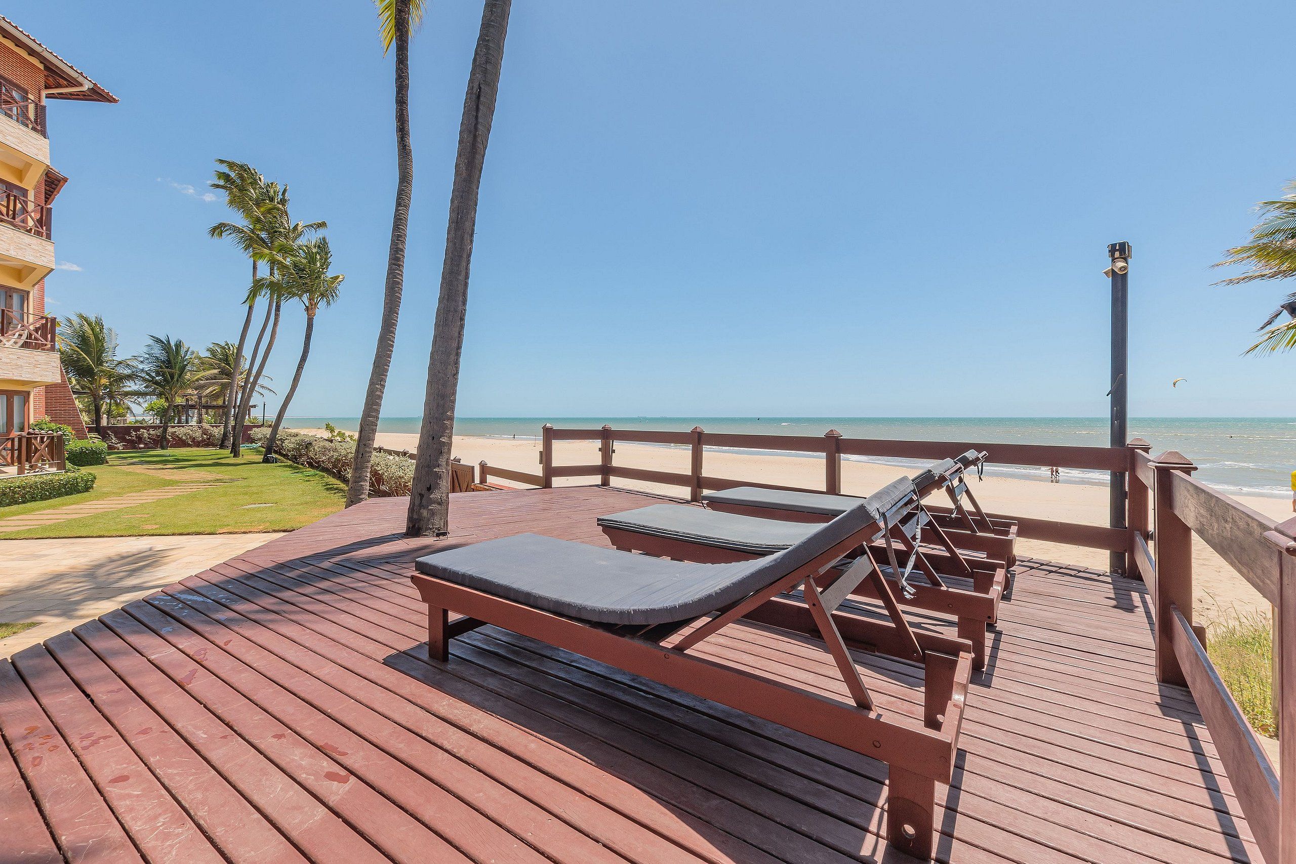 Um deck de madeira com espreguiçadeiras com vista para uma praia.