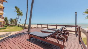 Um deck de madeira com espreguiçadeiras com vista para uma praia.