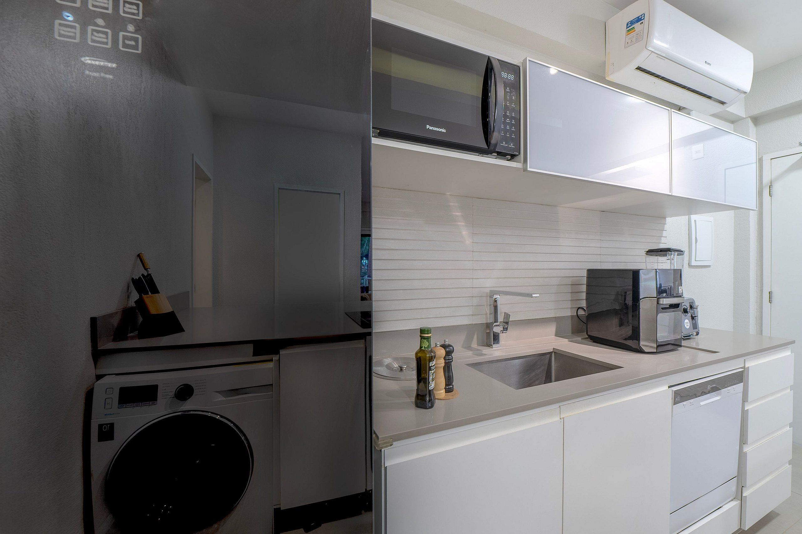 Cocina compacta con lavadora, microondas, cafetera y fregadero.