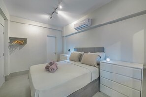 Een hotelkamer met een bed, nachtkastjes, een kledingkast, een airconditioning en een plafondlamp.