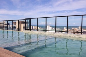 An infinity pool with a city view, surrounded by a glass railing. - Move #801 - Apartment With Balcony by Carpediem (João Pessoa)