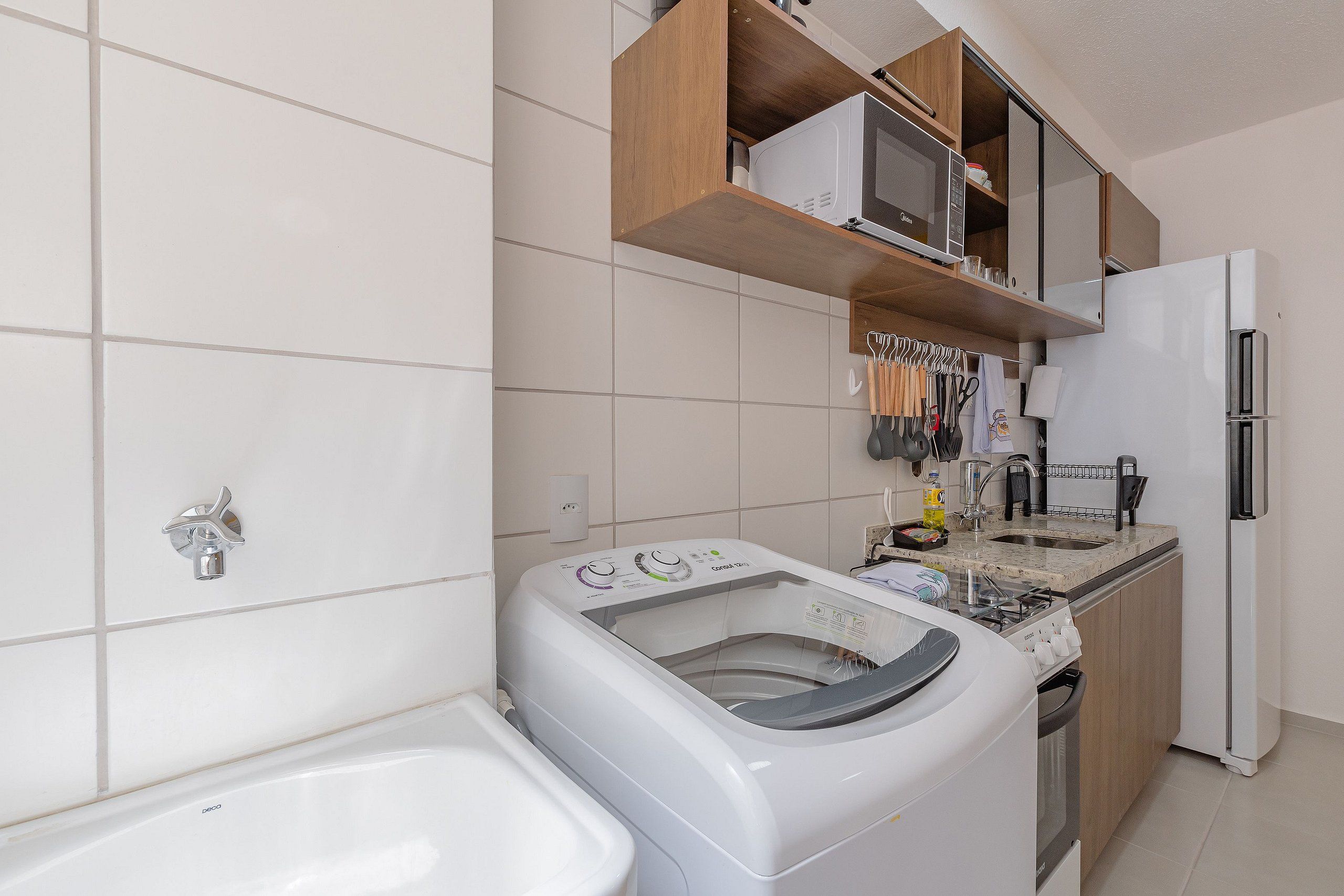A compact kitchen with a washing machine, a refrigerator, and a countertop with various kitchen utensils.