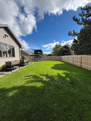 A backyard with a wooden deck, a lawn, and a house. - Spacious 4-bedroom house in lovely Neenah- 17 min from EAA (Neenah)