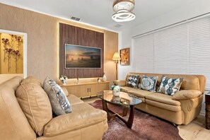 A living room with a sofa, a coffee table, a TV, and a lamp. - Windsor Hills 6BR Disney Home With Themed Rooms (Kissimmee)