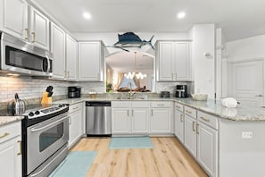 A modern kitchen with white cabinetry, stainless steel appliances, and a central island. - Windsor Hills 6BR Disney Home With Themed Rooms (Kissimmee)