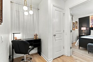 A modern bedroom with a wooden floor, a black desk with a chair, a bed with a grey upholstered bench, and a painting on the wall. - Windsor Hills 6BR Disney Home With Themed Rooms (Kissimmee)