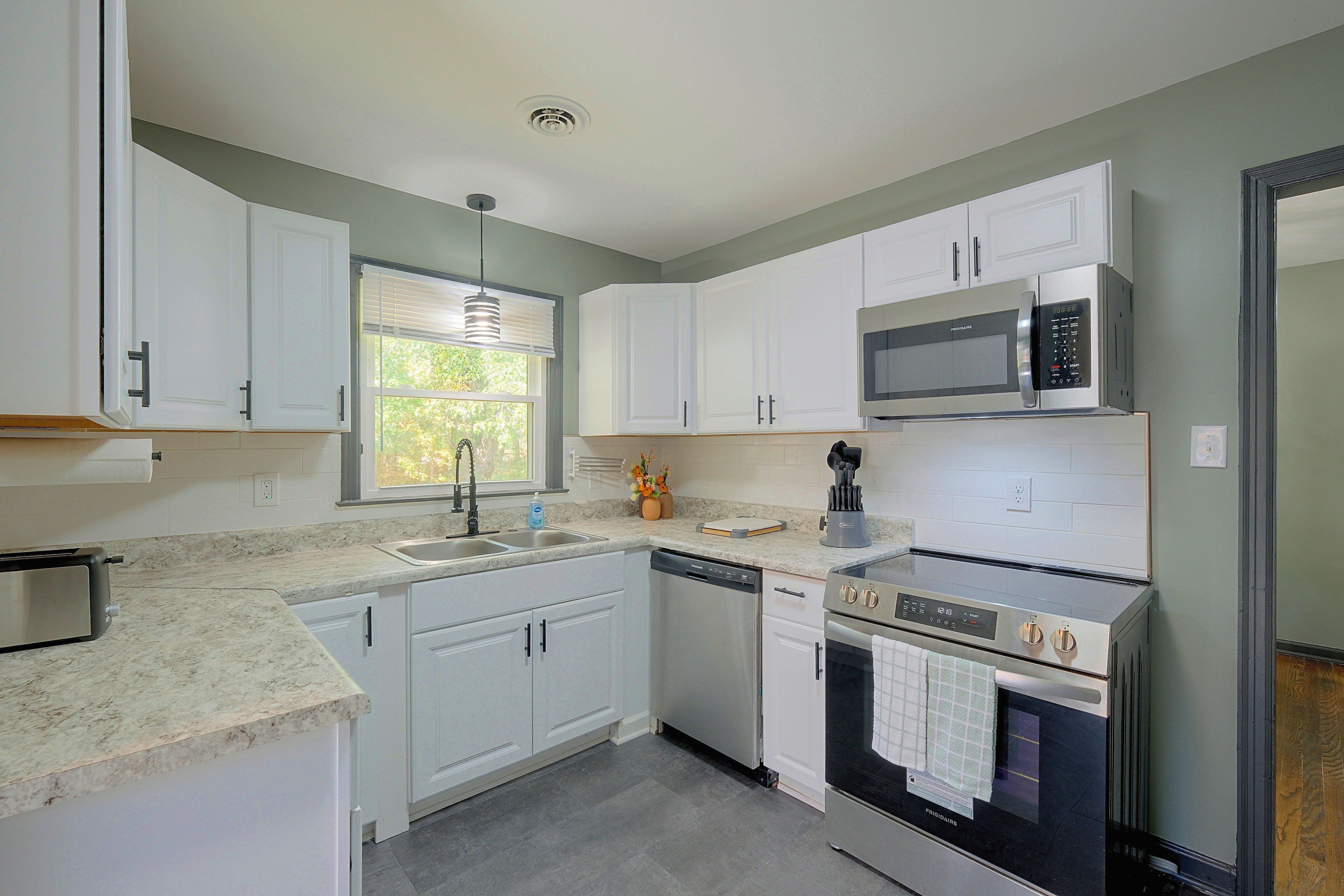 A modern kitchen with white cabinetry, a built-in microwave, a dishwasher, and an oven.