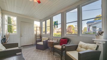 A sunroom with wicker furniture, large windows, and a view of the neighborhood.